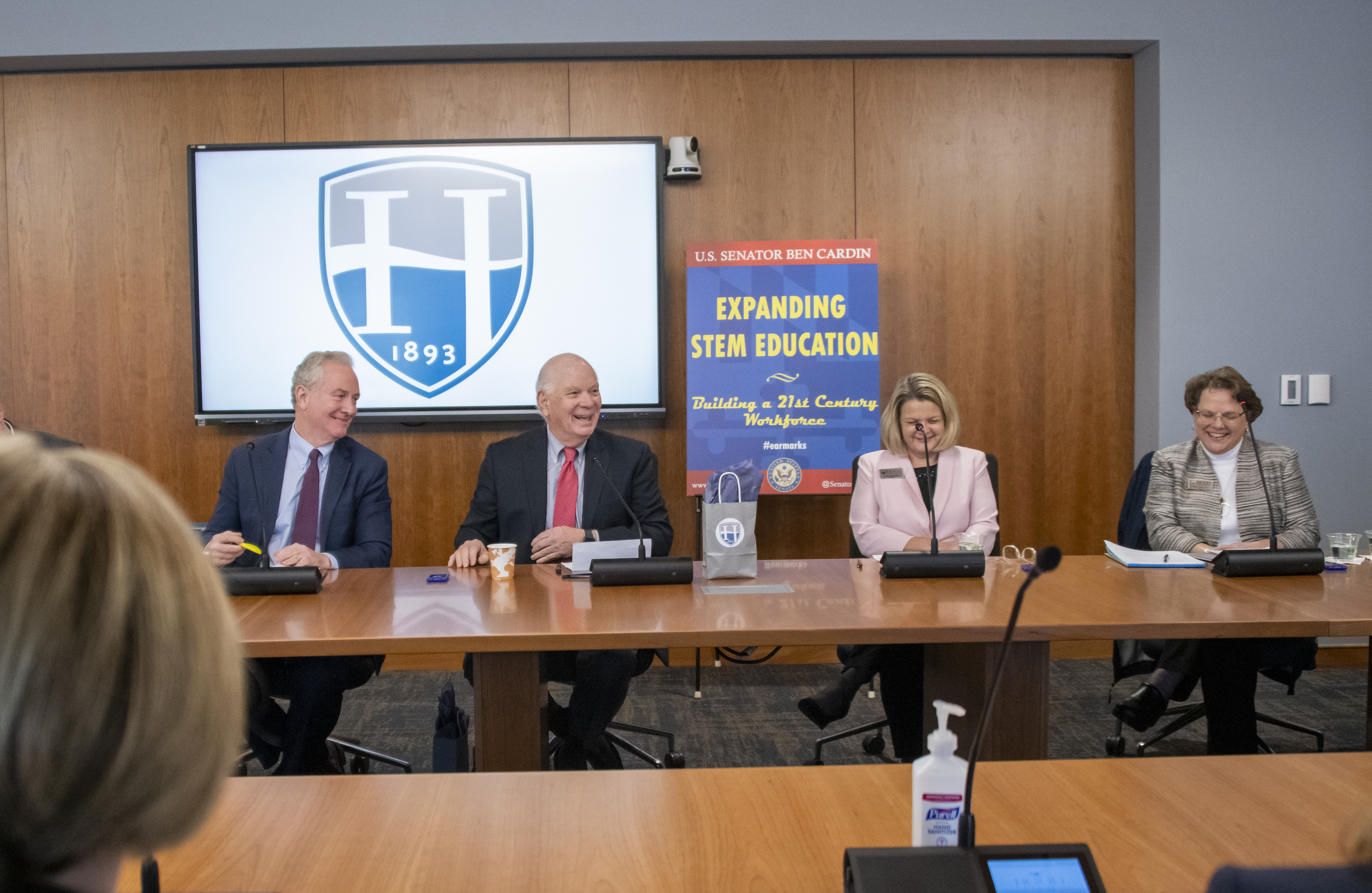 Senators Cardin and Van Hollen laugh white sitting at a conference table in the Beneficial-Hodson Library and Learning Commons