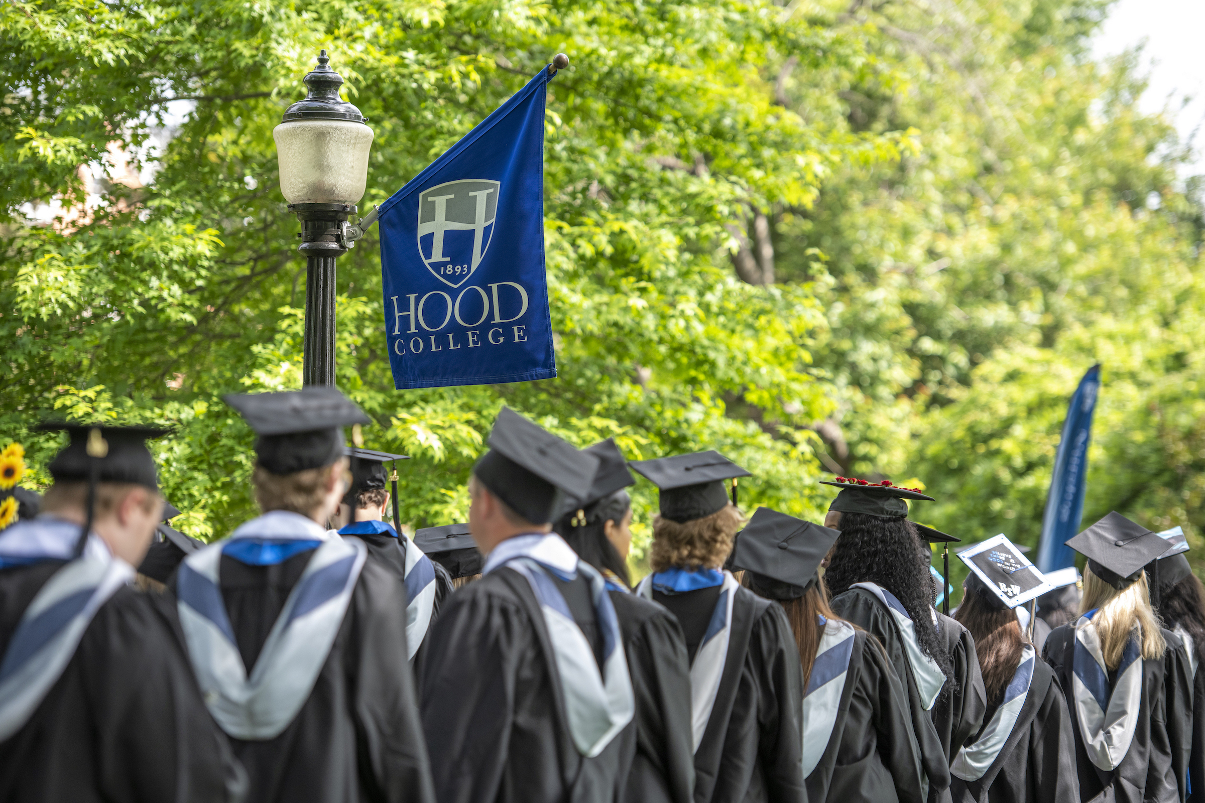 A crowd of Hood College graduates gather on the quad.