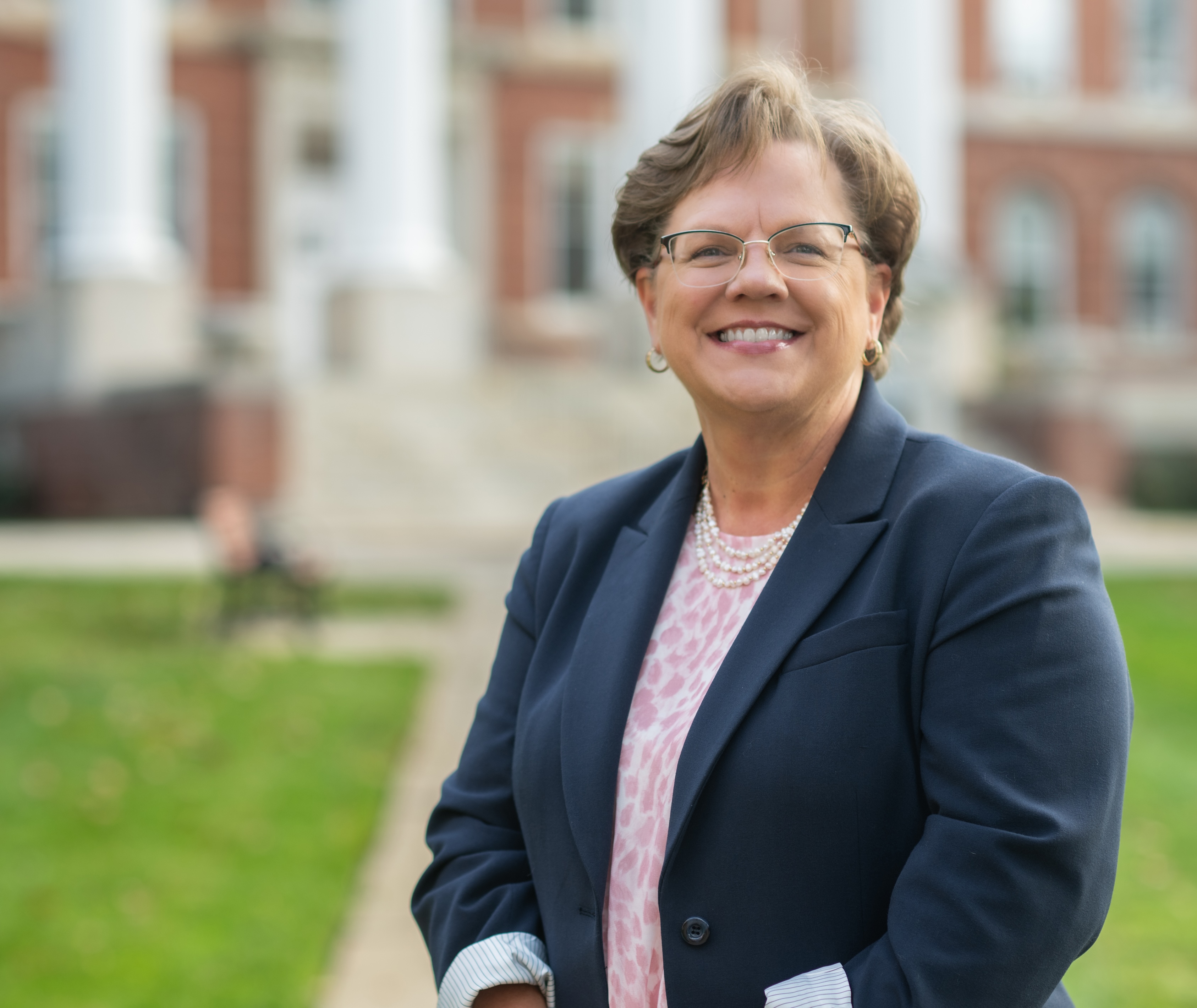 Headshot of Debbie Ricker standing in front of Alumnae Hall