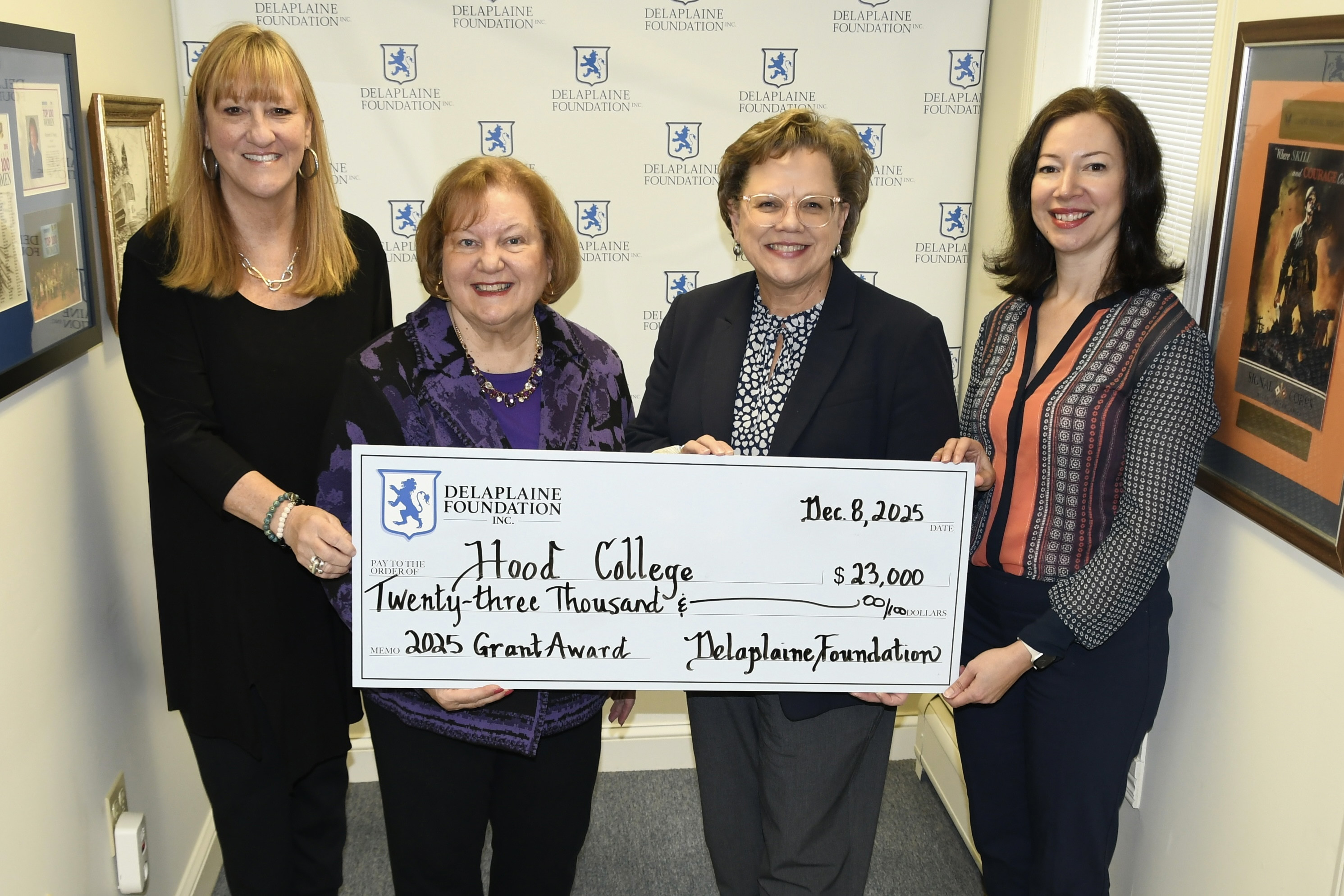 Representatives from Hood College and Delaplaine Foundation Inc. hold a large check