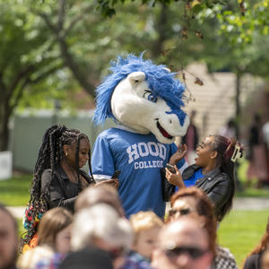 Hood's mascot, Blaze, taking a photo with a family at 2023 commencement