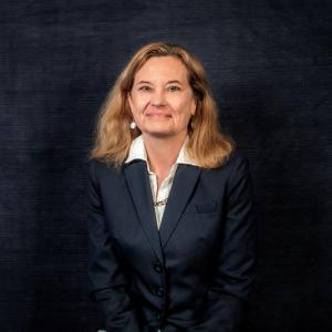 a headshot of anne davis in front of a blue background