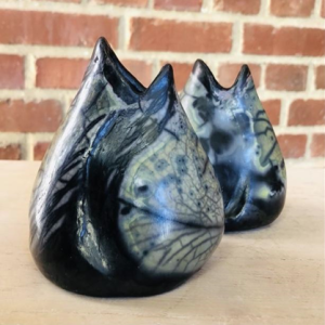 Two black and grey fish-shaped vases on a wooden counter