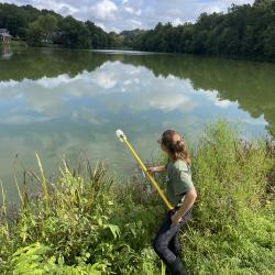 student sampling lake with pole