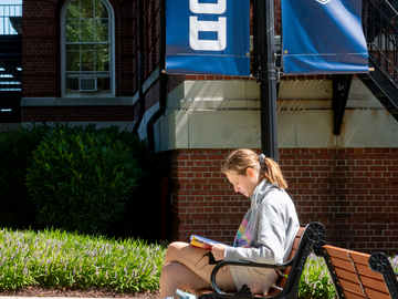 Student reading at a bench