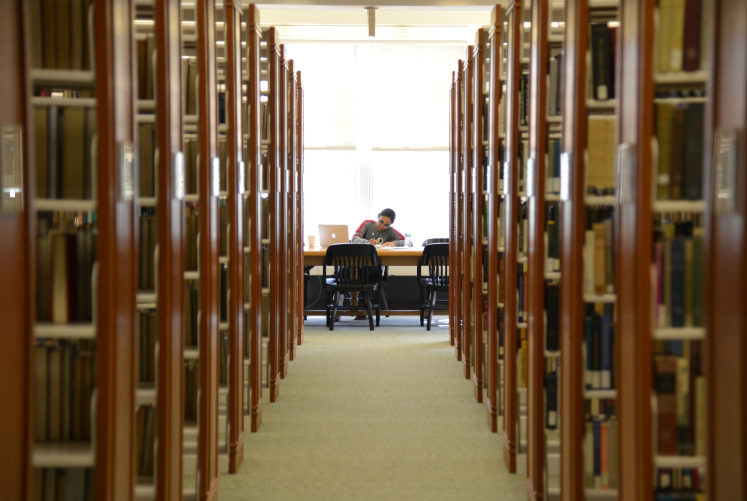 A student, surrounded by books, studies within the Beneficial-Hodson Library and Learning Commons