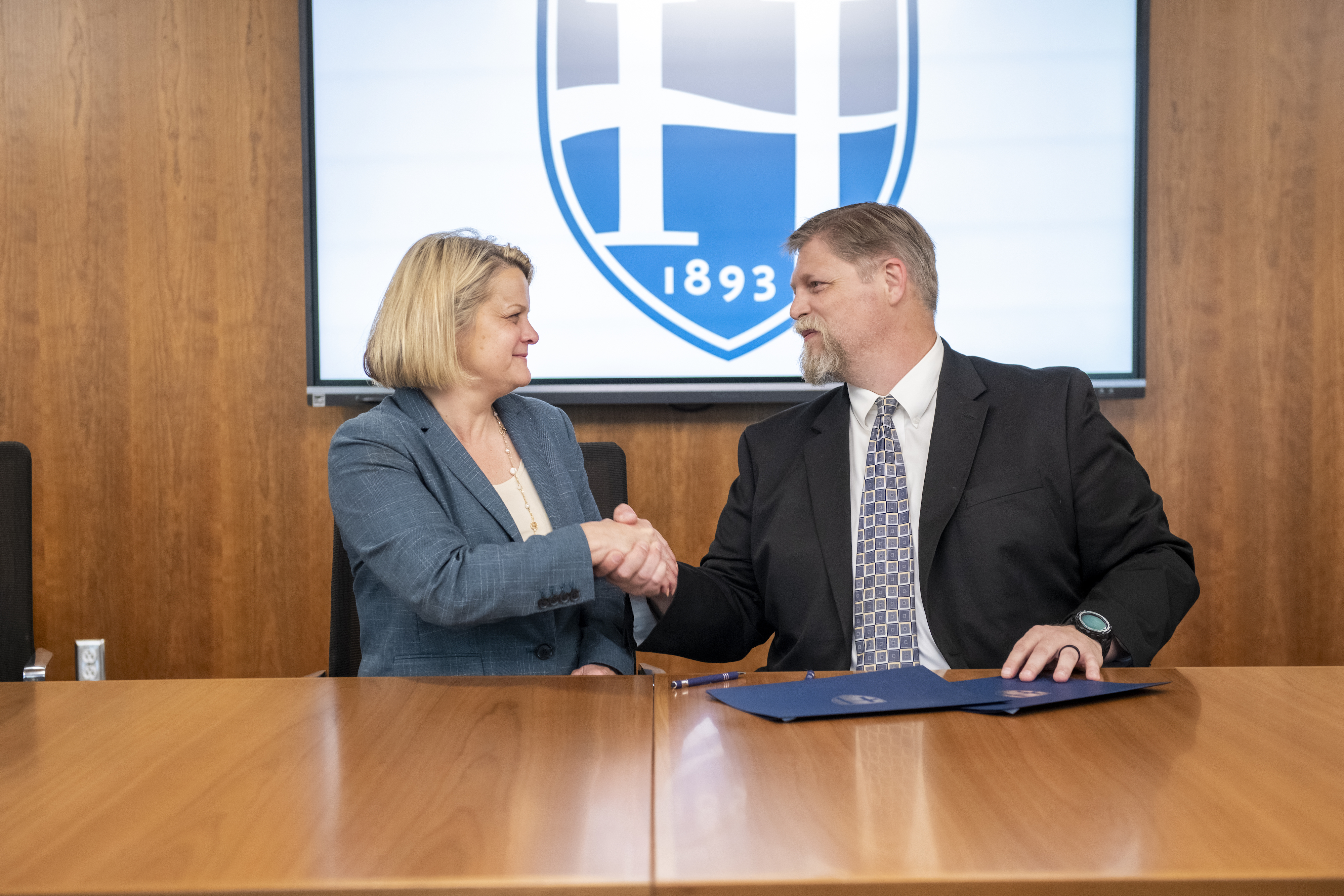 Andrea E. Chapdelaine, president of Hood College, and Patrick Haley, chairman and co-founder of ScienceWerx, shake hands within the Hodson Library and Learning Commons