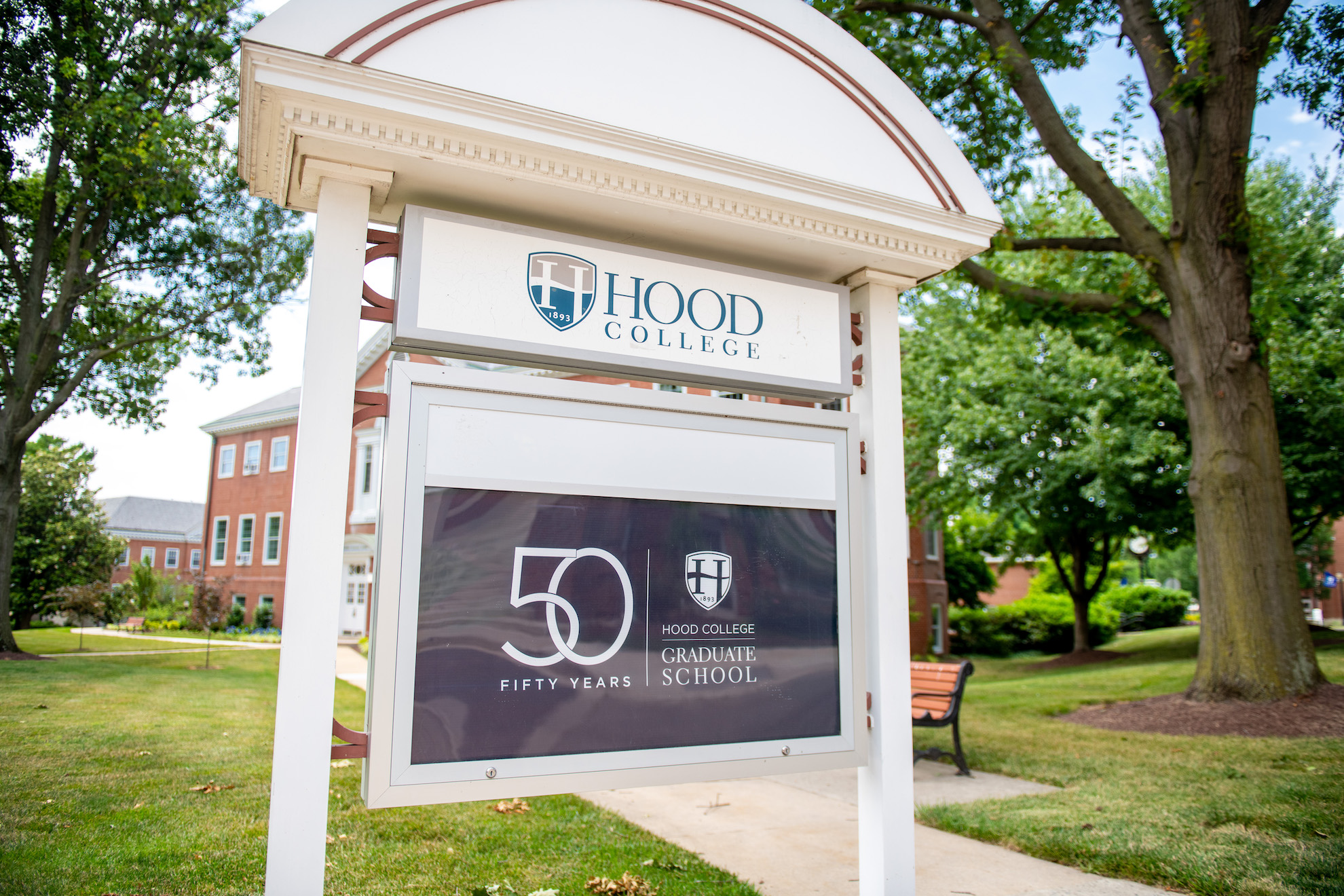A kiosk outside of the Apple Building on Hood's campus. Inside the kiosk, a poster celebrates Hood College Graduate School's 50th anniversary