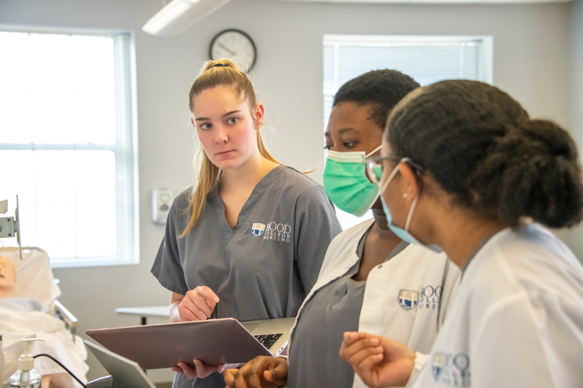 Hood nursing students gather to discuss a patient's symptoms in a simulated lab.