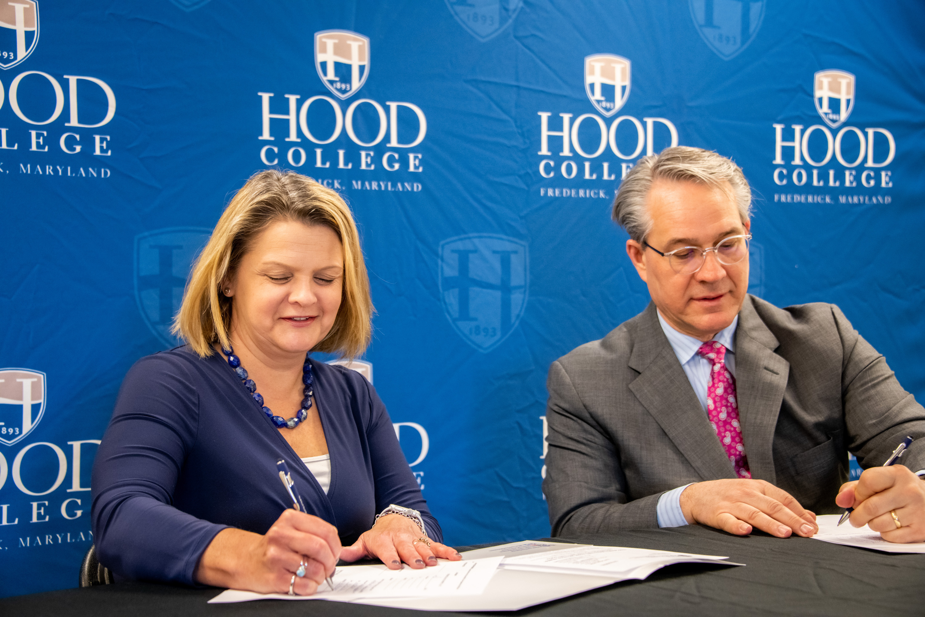 President Andrea Chapdelaine and CEO Tom Kleinhanzl sign a lease in front of a blue backdrop