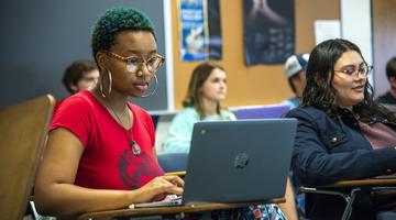 A student working at a laptop in a classroom