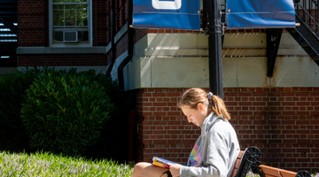 Student reading at a bench