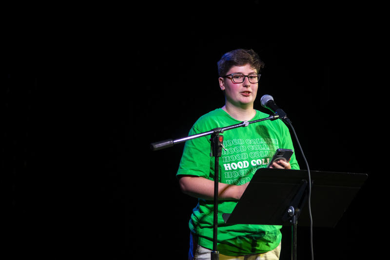 A creative writing student reading their work at an open mic.