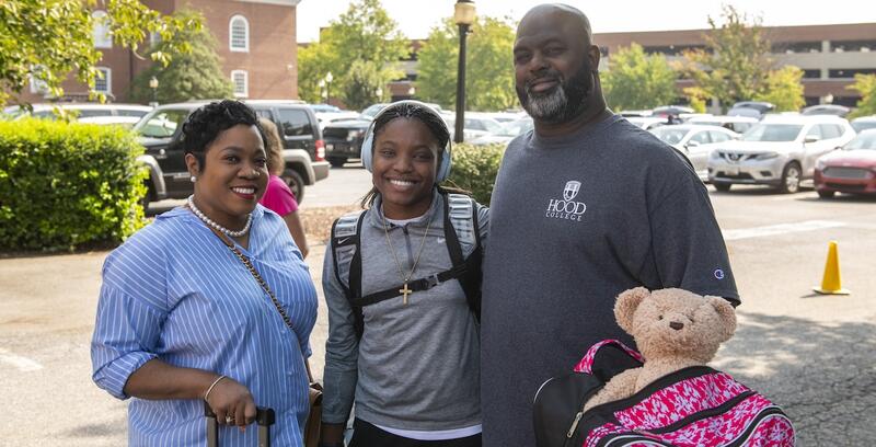 A family poses outside of Smith Hall during Move In Day in 2024