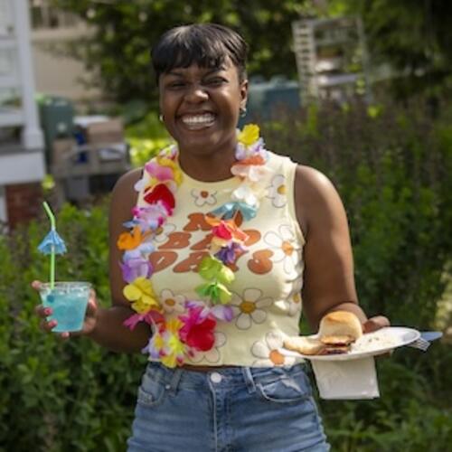 A student holding a mocktail smiles towards the camera