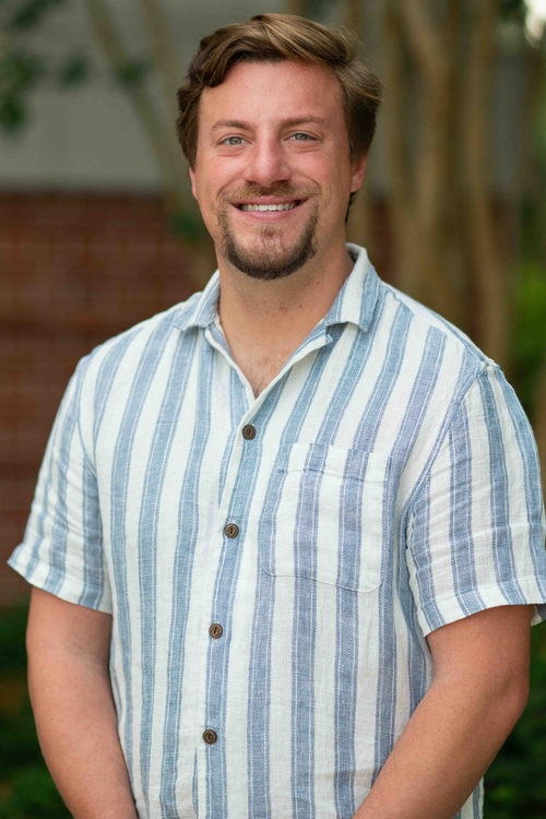 this is a photo of a man with a goatee and a blue-striped shirt.
