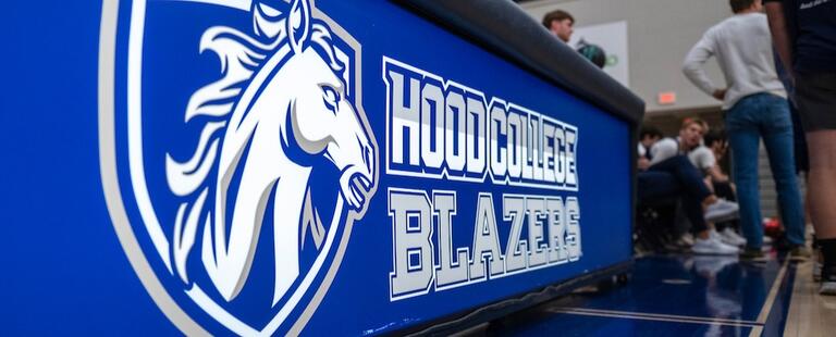 Illuminated signage that reads "Hood College Blazers" in blue and white alongside the Hood College Athletics logo