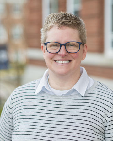 A vertical headshot of Michelle Gricus smiling on a sunny day