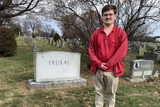 Luke Jones '23 standing in front of President Truxal's headstone in a cemetary