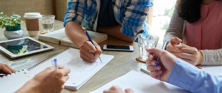 group of professionals sitting at a table working on their MBA work