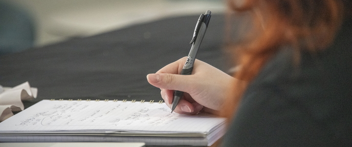 A student taking notes in a creative writing workshop.