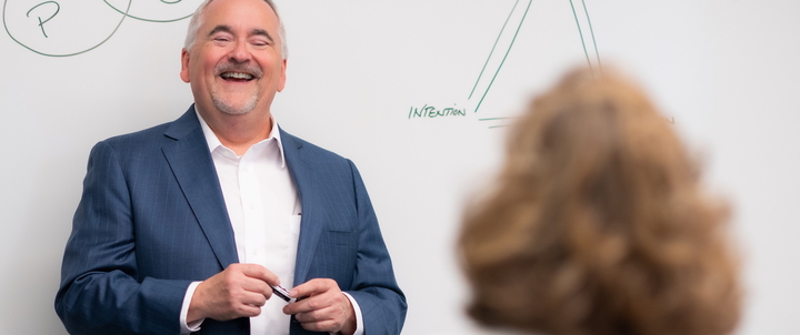 A professor giving a presentation in front of a whiteboard.