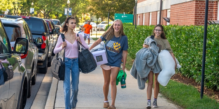 Hood College studenet athletes carry blankets, pillow and other items as they move in to their residence hall.
