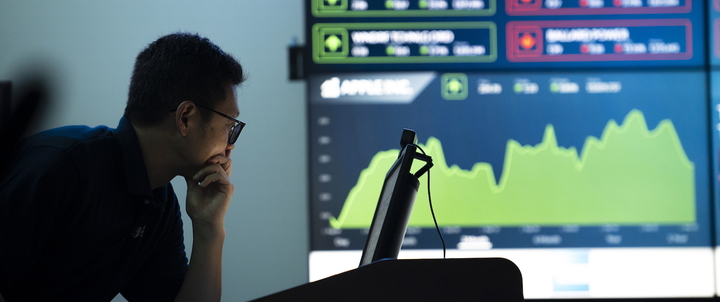 A professor examining a computer in the trading room.