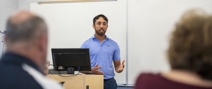 A Hood student presenting in front of a whiteboard.