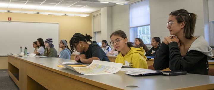 Mathematics students studying a map in a classroom.