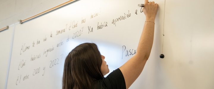 A TA writing on the whiteboard during a Spanish class.