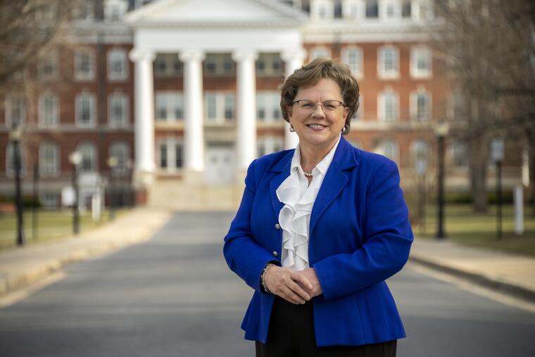 President Debbie Ricker stands outside with Alumnae Hall's four columns behind her