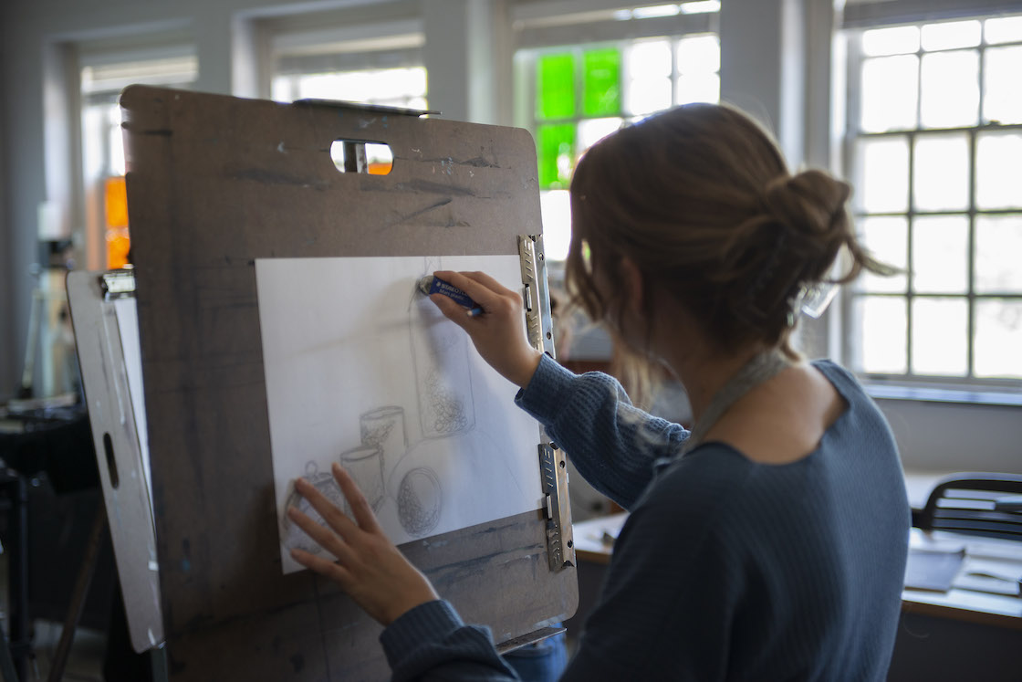 A student working on a drawing at an easel